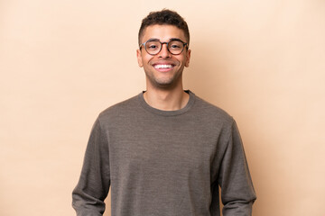 Young Brazilian man isolated on beige background laughing