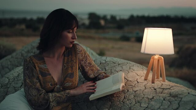 Girl reads book on the mountain with abat jour at night