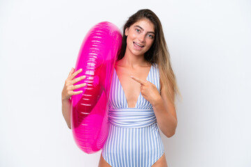 Young woman in swimsuit holding an air mattress donut isolated on white background and pointing it
