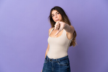 Young caucasian woman isolated on purple background showing thumb down with negative expression