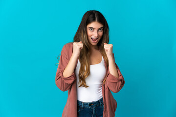 Fototapeta premium Young caucasian woman isolated on blue background celebrating a victory in winner position