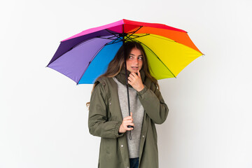 Young caucasian woman holding an umbrella isolated on white background looking to the side and smiling