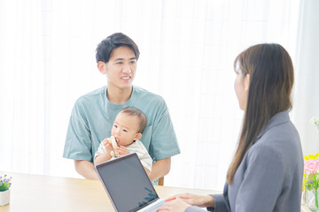 Obraz premium リビングで赤ちゃんの父親と話す女性外交員