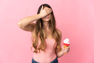 Young caucasian woman with a cornet ice cream isolated on pink background covering eyes by hands....