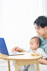 赤ちゃんとノートパソコンを見る父親