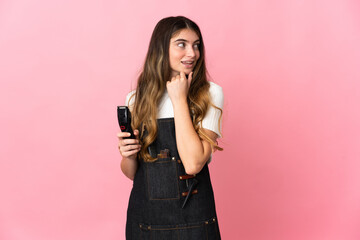 Young hairdresser woman isolated on pink background looking to the side and smiling