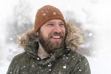 Closeup mature man bearded winter coat with fur collar and brown knitted hat snow outdoor. Positive...