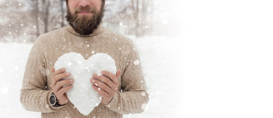 Male hands with heart of snow in winter day. Man in knitted sweater holds snow heart. Love sport...