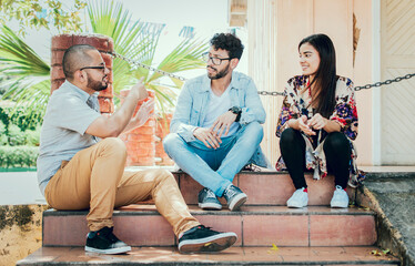 Three young friends talking sitting on the stairs. Three teenage friends talking sitting on the stairs, Three young people sitting on the street talking. Concept of friends talking