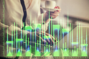 Double exposure of businesswoman hands typing on computer and financial graph hologram drawing. Stock market analysis concept.