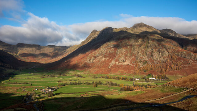 Colorful vibrant Autumn landscape image looking from Pike O'Blisco towards Langdale Pikes and Range with beautiful sungiht on mountains and valley