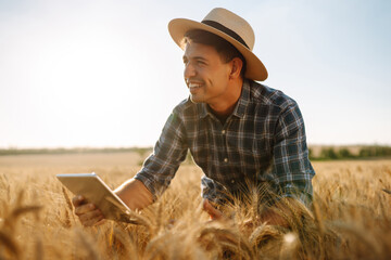 Farmer on a wheat field with a tablet in his hands. Smart farm. Agriculture, gardening or ecology concept