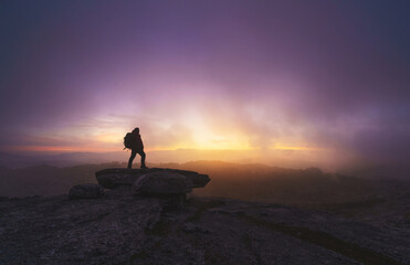 Silhouette of a man explorer on some mountain rocks at sunrise