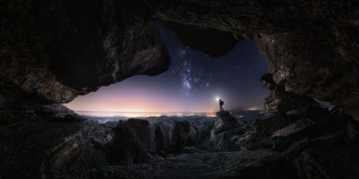 Unrecognizable traveler near cave at night