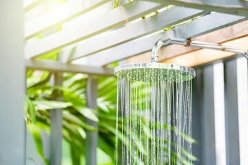 sunlight effect shine in to Outdoor pool bathroom open air style  with rain shower beside swimming pool in sunny day.