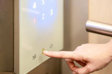 She is using her index finger to press the floor number that digital buttons in the elevator.