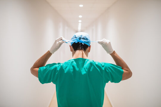 Anonymous surgeon tying medical cap in clinic corridor