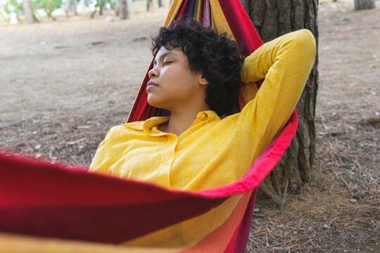 Calm young woman resting in hammock in park