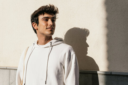 Stylish man standing on concrete wall in city