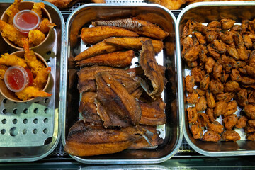 Trays containing a variety of Dutch fast food fish dishes. Shrimp in batter, deep fried muscles, baked gurnard which is called Gebakken poon in the Netherlands