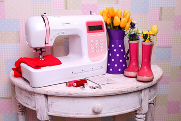 Composition from a sewing machine. Mannequin, flowers on a retro table and threads. Sewing supplies and composition with a sewing machine in the interior. With the letter M. for the fashion magazines