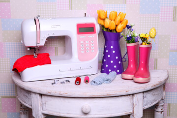 Composition from a sewing machine. Mannequin, flowers on a retro table and threads. Sewing supplies and composition with a sewing machine in the interior. With the letter M. for the fashion magazines