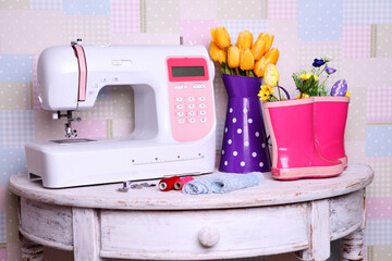 Composition from a sewing machine. Mannequin, flowers on a retro table and threads. Sewing supplies and composition with a sewing machine in the interior. With the letter M. for the fashion magazines