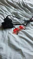 pink glasses on a white background.glasses on a white cravate.glasses and camera on a white background.camera on the bed.camera and glasses on a white background