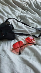 pink glasses on a white background.glasses on a white cravate.glasses and camera on a white background.camera on the bed.camera and glasses on a white background.two glasses on the bed