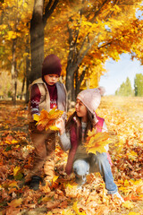 happy boy and girl laughing on the background of autumn leaves in the park. Family Having Fun...