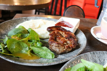 pork steak with sauce and herbs on a plate on a wooden table
