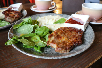 pork steak with sauce and herbs on a plate on a wooden table