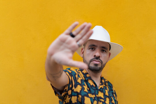 Hispanic man in hat showing stop gesture