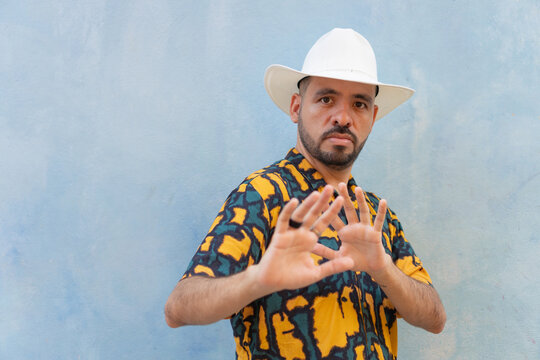 Hispanic man in hat showing stop gesture