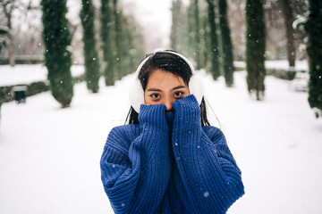 Millennial Asian woman in knitwear in winter park