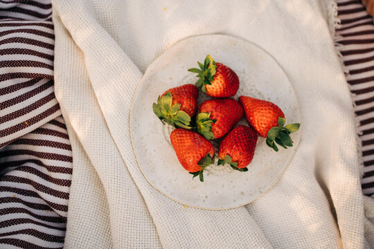 Delicious fresh strawberries on plate on crumpled plaid