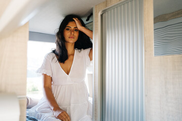 Hispanic woman sitting on bed in van