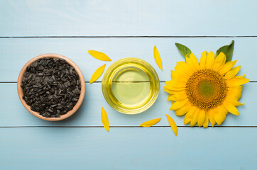 Sunflower oil, seeds and flower on wooden background