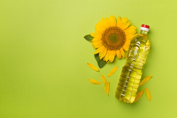 Sunflower oil and flower on color background, top view