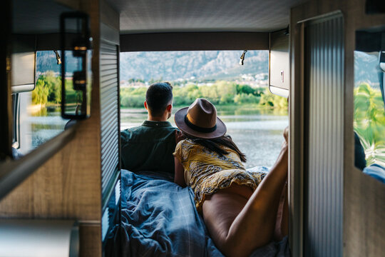 Traveling couple relaxing in van near river
