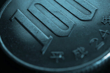 Translation: year of issue 2012. Japanese 100 yen coin close-up. Dark blue tinted background....