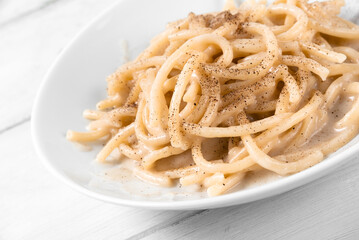 Primo piano di deliziosi spaghetti cacio e pepe, tipica ricetta di pasta della cucina romana, cibo italiano 