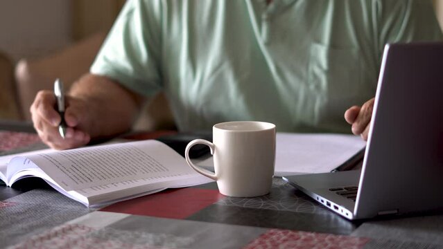 Faceless man sitting studying with books and laptop. Study and work concept.