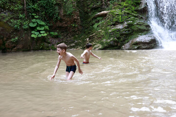 Brothers bathing in Rufabgo stream next to waterfall Shum
