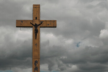 A large cross on a background of dark clouds. Cross with free space for text