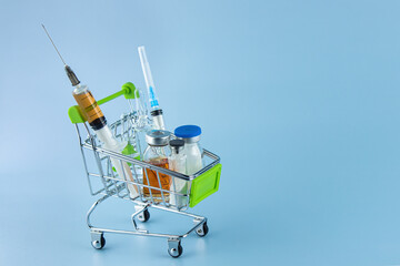 On a blue background in a shopping cart are various medical supplies, medicines.  Lots of free space