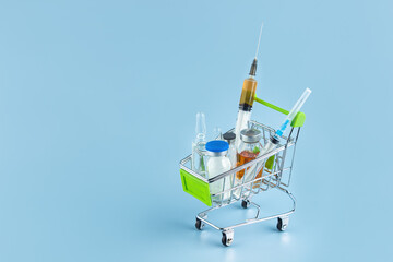 On a blue background in a shopping cart are various medical supplies, medicines.  Lots of free space