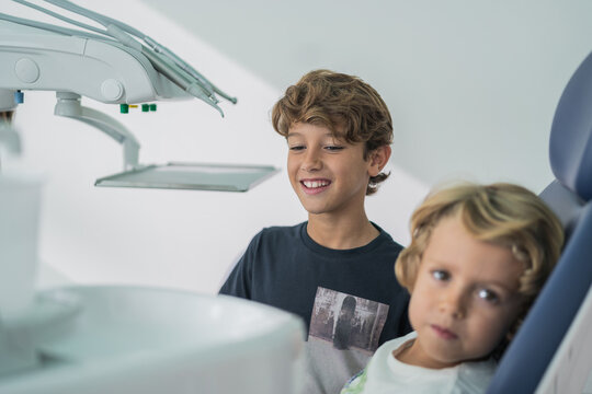 Cheerful boy supporting brother in dental clinic