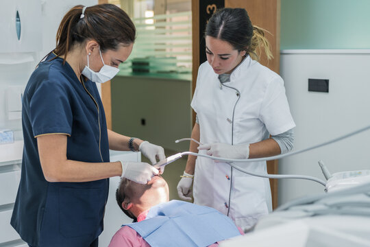 Dentist and nurse curing teeth of man