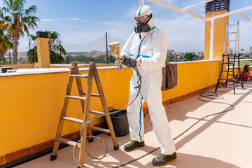 Male worker with aerograph renovating house